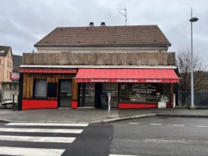 Store banne réentoilé en rouge et blanc, installé sur une boucherie-charcuterie artisanale